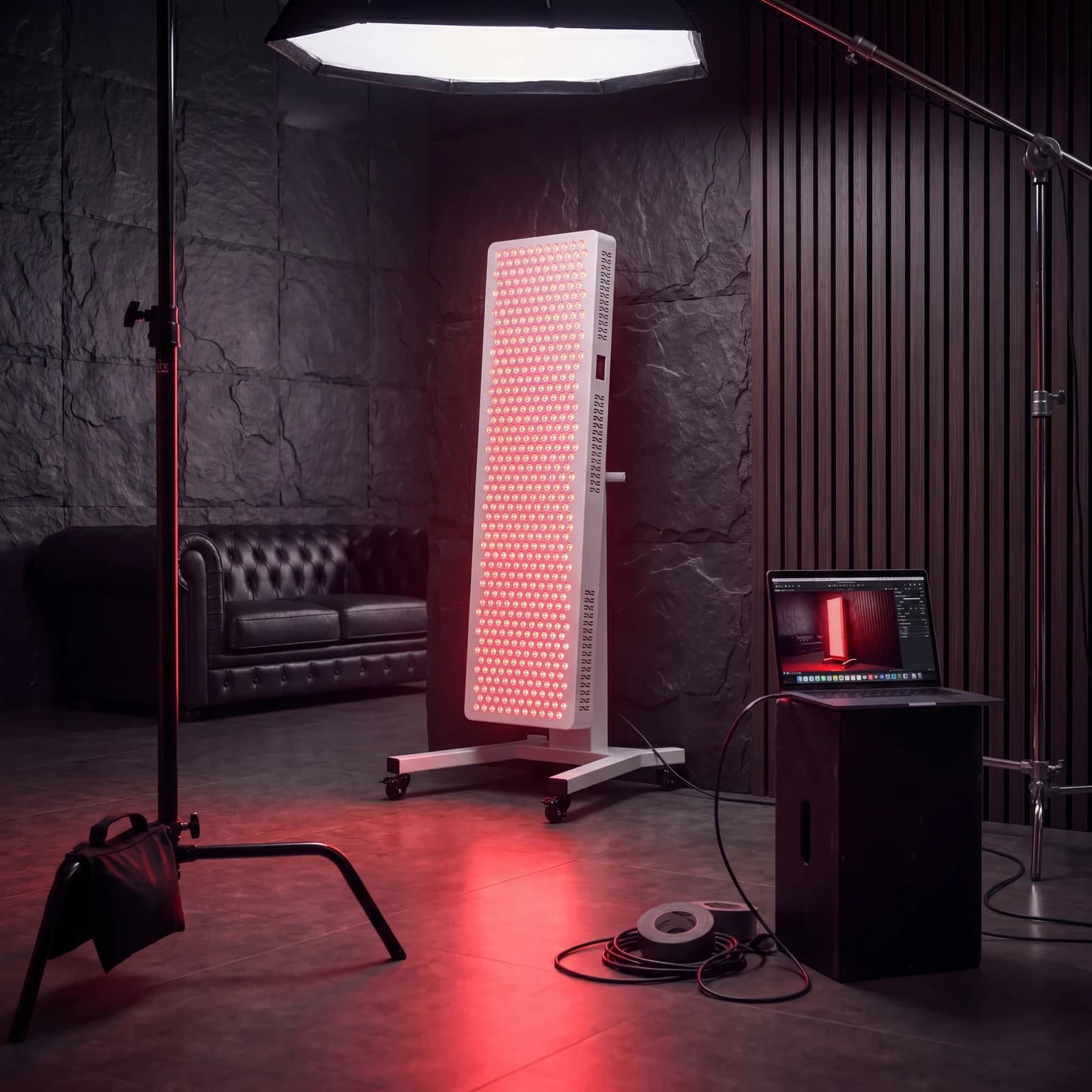 Hale RLPRO 2000 LED therapy panel powered on in a studio shoot — full LED grid glowing red, softbox + tethered preview station in the dark slate stone brand room